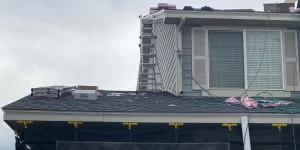 Residential roof installation in progress with ladders, tools, and roofing materials visible on the rooftop