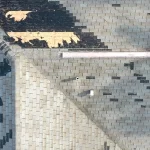 Aerial view of hail-damaged roof shingles showing missing granules and exposed spots after Colorado storm