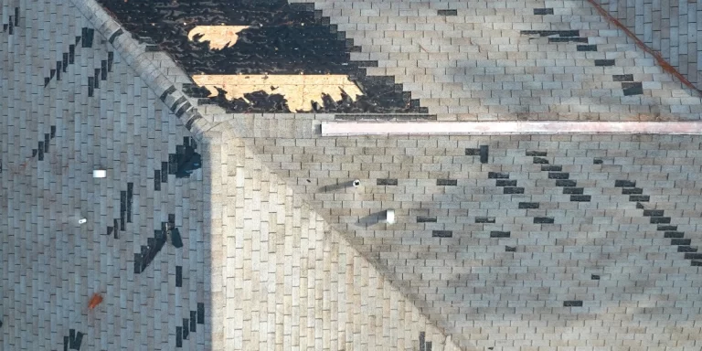Aerial view of hail-damaged roof shingles showing missing granules and exposed spots after Colorado storm