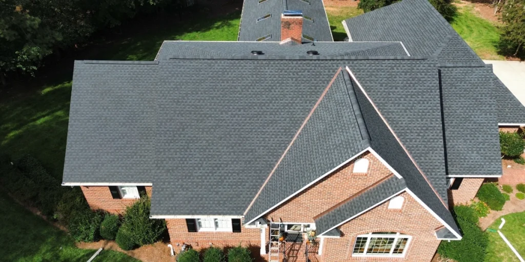 Aerial view of completed residential roof replacement with dark gray asphalt shingles on Colorado home