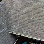 Asphalt shingle roof marked with chalk circles highlighting hail damage spots from a Colorado roof inspection